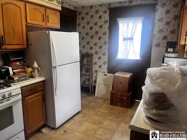 157 W Main St, Allegany, NY 14706 - kitchen featuring wallpapered walls, white appliances, light countertops, and brown cabinets