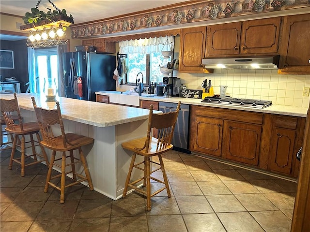 496 Burdick Medbury Rd, Norwich-Town, NY 13815 - kitchen with stainless steel appliances, under cabinet range hood, tasteful backsplash, light countertops, and a breakfast bar