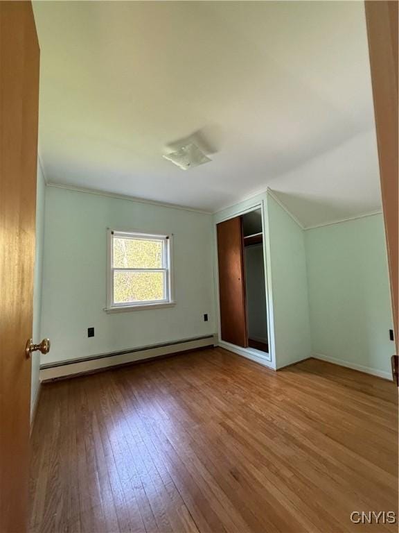 5877 State Route 233, Westmoreland, NY 13440 - unfurnished bedroom featuring baseboard heating, hardwood / wood-style floors, ornamental molding, a closet, and vaulted ceiling
