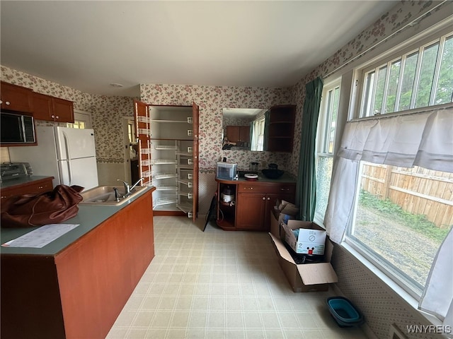 75 Main St, North Dansville, NY 14437 - kitchen featuring wallpapered walls, stainless steel microwave, healthy amount of natural light, freestanding refrigerator, and light flooring