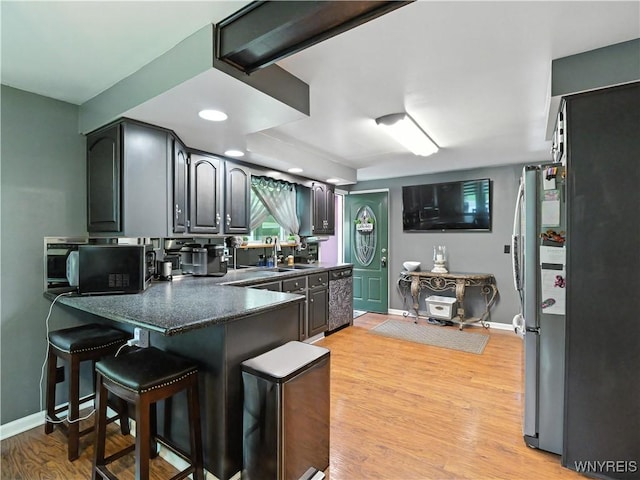 5137 William St, Lancaster, NY 14086 - kitchen with dishwashing machine, a peninsula, dark countertops, light wood-style flooring, and a breakfast bar