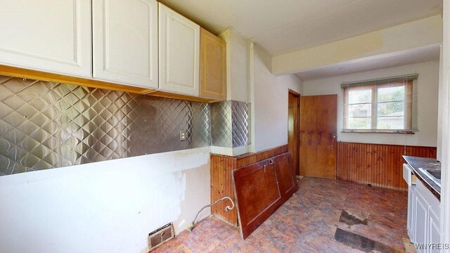 173 Hedley Pl, Buffalo, NY 14208 - kitchen featuring a wainscoted wall, wood walls, backsplash, and white cabinetry