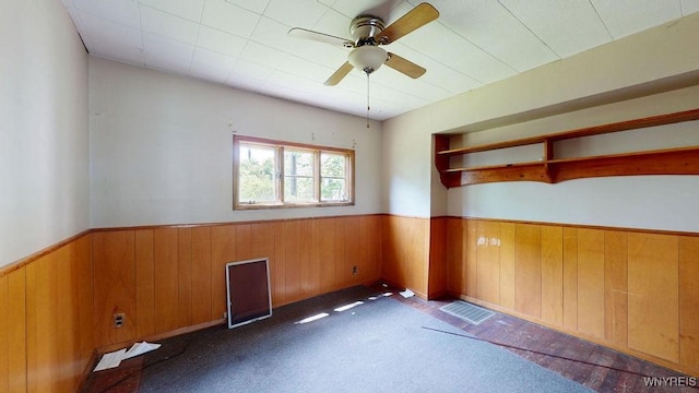 173 Hedley Pl, Buffalo, NY 14208 - spare room featuring a wainscoted wall, wood walls, ceiling fan, and carpet