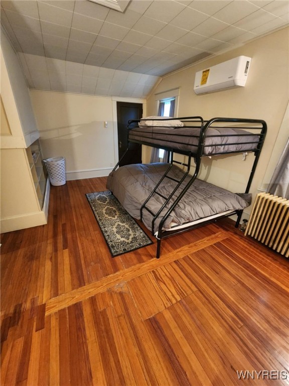 2207 Sheldon Dr, Allegany, NY 14706 - bedroom featuring a wall mounted AC, lofted ceiling, and hardwood / wood-style floors