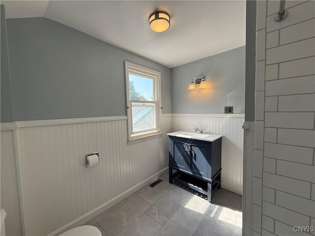 320 W 3rd St, Oswego-City, NY 13126 - bathroom featuring a wainscoted wall, vanity, lofted ceiling, and tile patterned floors