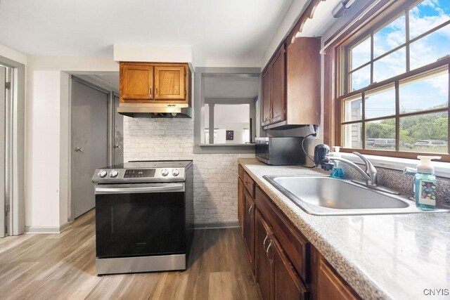 9 Lawrence Ave, New Hartford, NY 13413 - kitchen with appliances with stainless steel finishes, light wood-type flooring, under cabinet range hood, light countertops, and brown cabinetry
