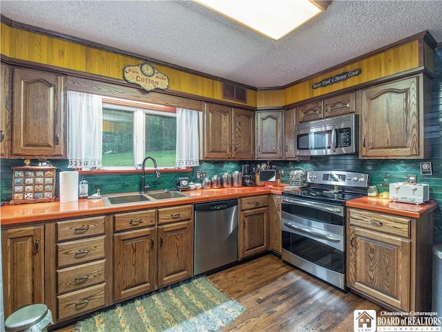5152 John Darling Rd, Conowingo, NY 14726 - kitchen featuring appliances with stainless steel finishes, a textured ceiling, decorative backsplash, dark wood-type flooring, and brown cabinetry