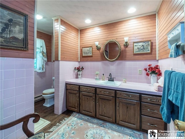 5152 John Darling Rd, Conowingo, NY 14726 - bathroom featuring vanity, tile walls, a baseboard radiator, wood finished floors, and wainscoting