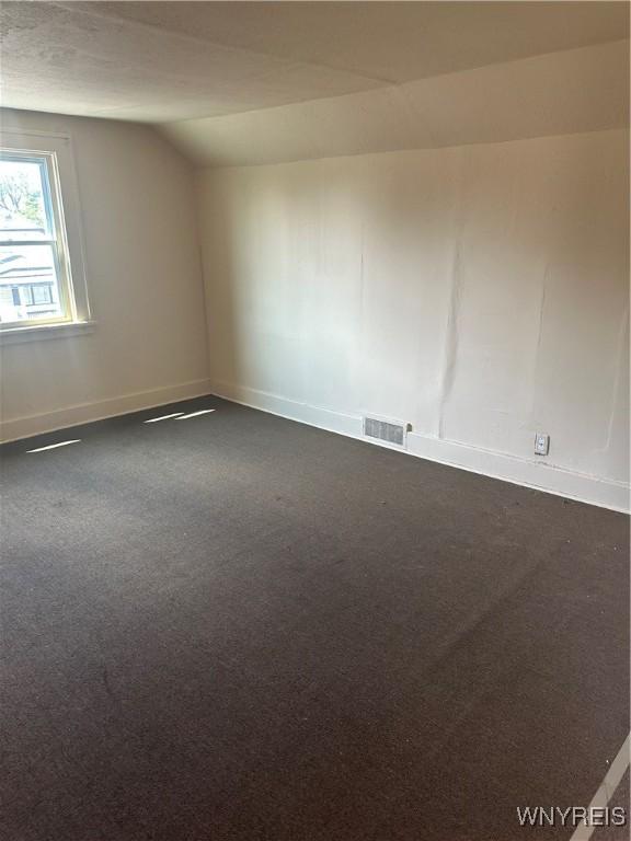 54 Decker St, Buffalo, NY 14215 - unfurnished room with vaulted ceiling and dark colored carpet