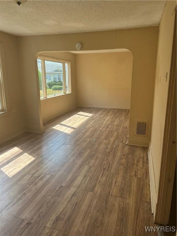 54 Decker St, Buffalo, NY 14215 - empty room with arched walkways, wood finished floors, and a textured ceiling