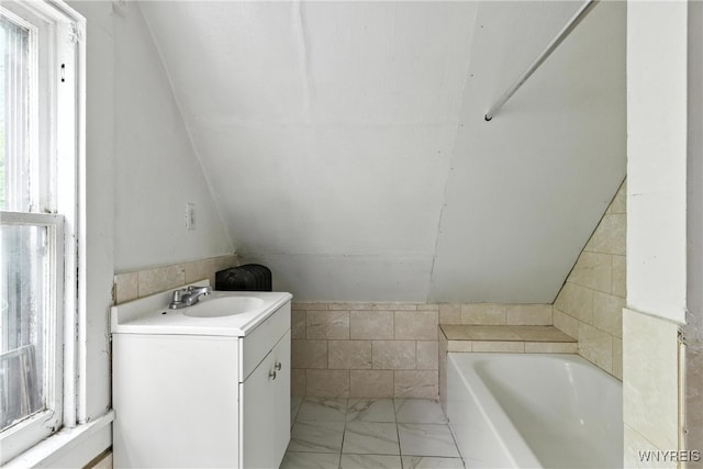 49 Urban St, Buffalo, NY 14211 - full bathroom featuring a tub to relax in, healthy amount of natural light, marble look tiles, vanity, and lofted ceiling