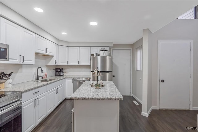 8433 Bubbling Springs Dr, Clay, NY 13027 - kitchen with appliances with stainless steel finishes, dark wood finished floors, white cabinets, a kitchen island, and light stone counters