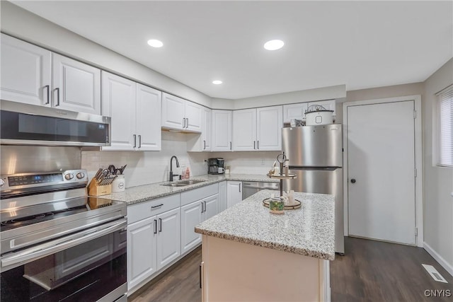 8433 Bubbling Springs Dr, Clay, NY 13027 - kitchen with stainless steel appliances, white cabinetry, dark wood finished floors, a kitchen island, and light stone countertops