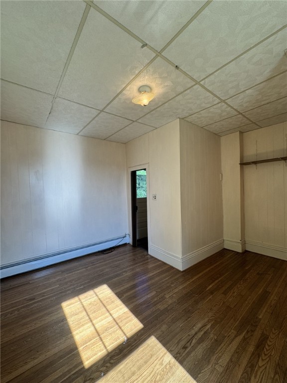 2 2nd St, Eldred, PA 16731 - spare room with a baseboard heating unit, wood finished floors, a drop ceiling, and wooden walls