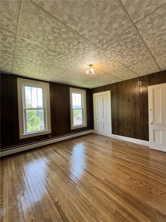 2 2nd St, Eldred, PA 16731 - empty room with a baseboard radiator, wood-type flooring, and wood walls