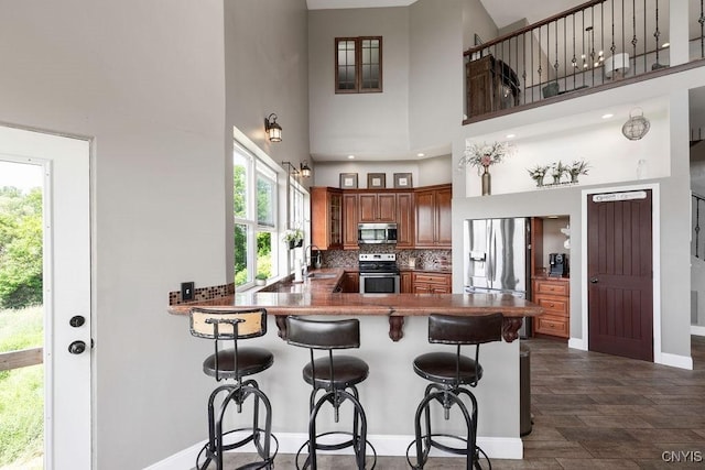 3785 Ransom Rd, Pompey, NY 13078 - kitchen with appliances with stainless steel finishes, brown cabinetry, a peninsula, backsplash, and a breakfast bar