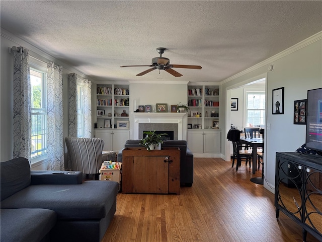 6303 Palmiter Rd, Alfred, NY 14803 - living area with a textured ceiling, wood finished floors, crown molding, a ceiling fan, and a tile fireplace