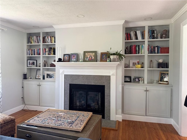 6303 Palmiter Rd, Alfred, NY 14803 - living room with wood finished floors, a textured ceiling, a tile fireplace, ornamental molding, and built in shelves
