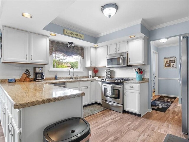 27 Black Spruce Ct, Greece, NY 14616 - kitchen with stainless steel appliances, a peninsula, light wood-style flooring, white cabinetry, and ornamental molding