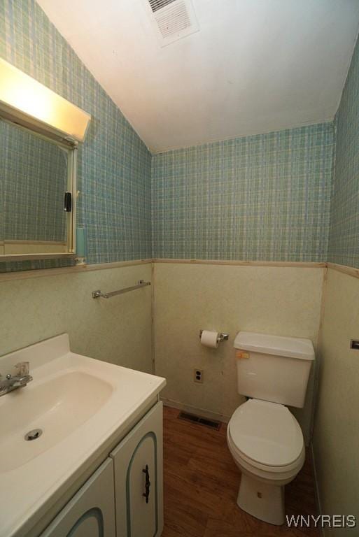 3840 Coomer Rd, Newfane, NY 14108 - bathroom featuring wallpapered walls, vanity, vaulted ceiling, wood finished floors, and a wainscoted wall