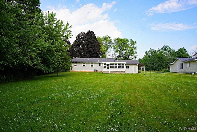 3840 Coomer Rd, Newfane, NY 14108 - back of property with a lawn and view of wooded area