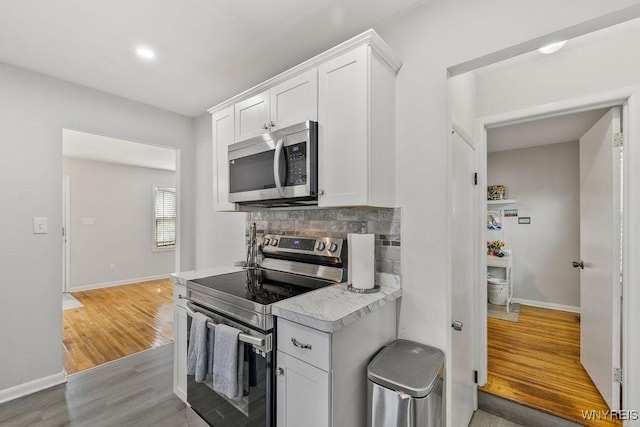 503 Kohl St, North Tonawanda, NY 14120 - kitchen featuring appliances with stainless steel finishes, light countertops, light wood finished floors, white cabinets, and backsplash