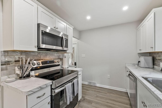 503 Kohl St, North Tonawanda, NY 14120 - kitchen with stainless steel appliances, tasteful backsplash, light wood-style floors, recessed lighting, and white cabinets