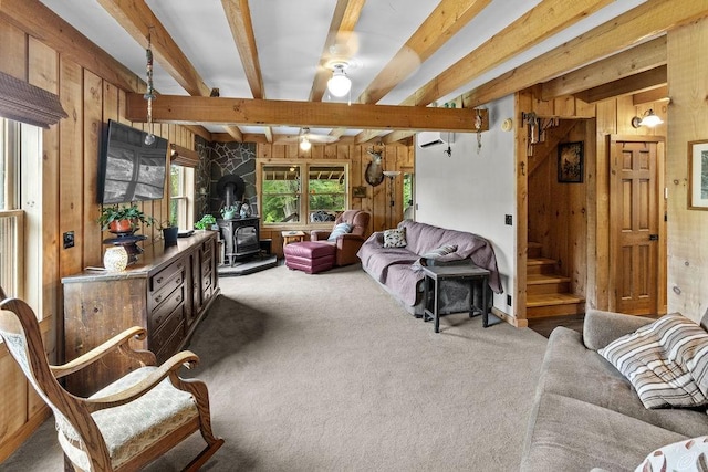 485 Spring Valley Rd, Delhi, NY 13753 - carpeted living area featuring wooden walls, a wood stove, beam ceiling, stairs, and ceiling fan