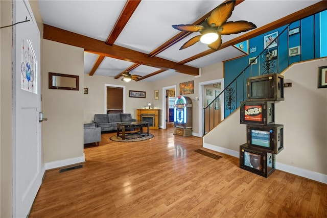 703 N Perry St, Dix, NY 14891 - living area with ceiling fan, a fireplace, beam ceiling, stairs, and light wood-style floors