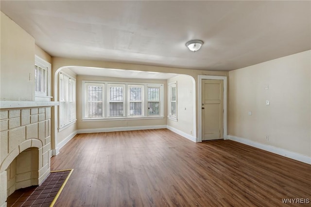 210 Carl St, Buffalo, NY 14215 - unfurnished living room with arched walkways, dark wood-style flooring, and a tile fireplace