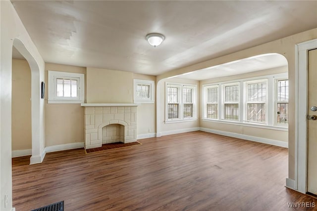 210 Carl St, Buffalo, NY 14215 - unfurnished living room featuring wood finished floors, arched walkways, and a tile fireplace