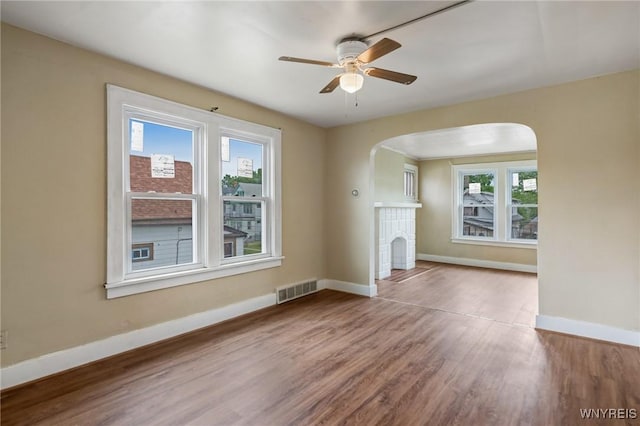 210 Carl St, Buffalo, NY 14215 - unfurnished living room with arched walkways, wood finished floors, a ceiling fan, and a brick fireplace