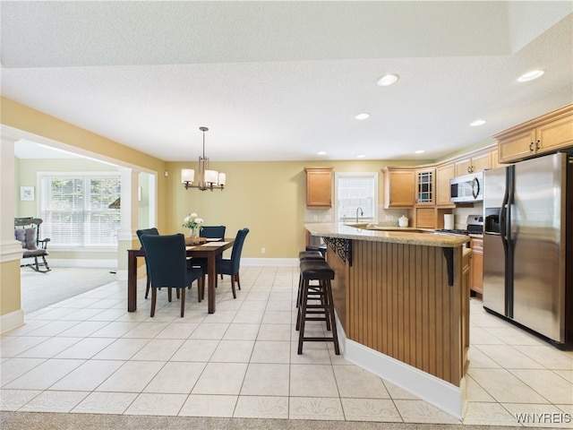 4166 Tisbury Ln, Hamburg, NY 14075 - kitchen featuring appliances with stainless steel finishes, a breakfast bar, a chandelier, glass insert cabinets, and recessed lighting