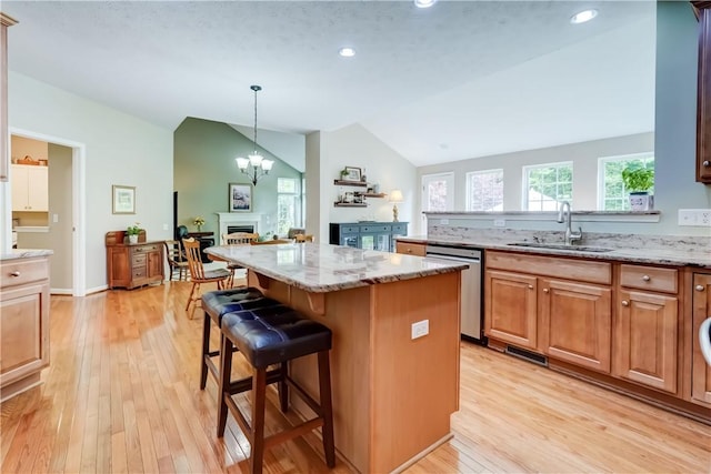 74 Chadwick Mnr, Perinton, NY 14450 - kitchen with stainless steel dishwasher, lofted ceiling, a breakfast bar area, a center island, and light stone counters
