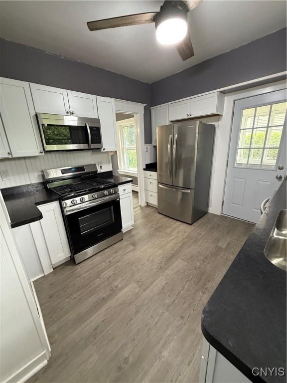37 Peacock St, Auburn, NY 13021 - kitchen with stainless steel appliances, dark countertops, ceiling fan, and white cabinets