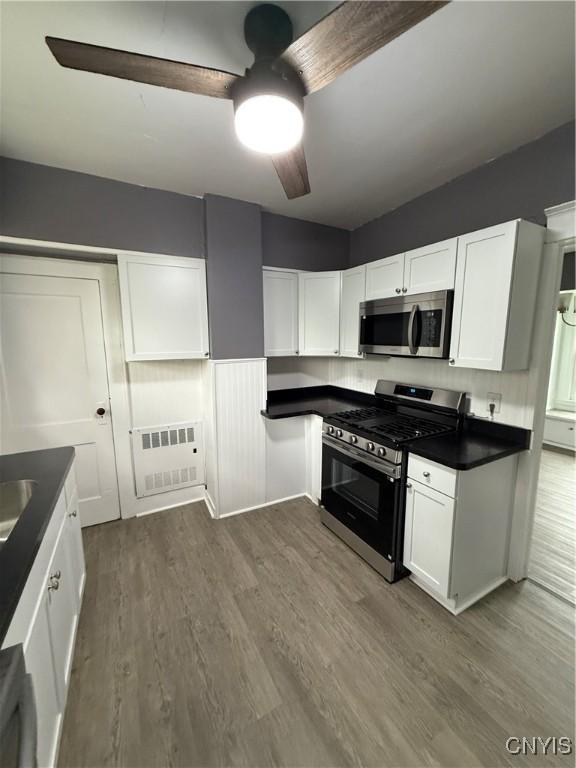37 Peacock St, Auburn, NY 13021 - kitchen with stainless steel appliances, ceiling fan, white cabinets, dark countertops, and dark wood-type flooring