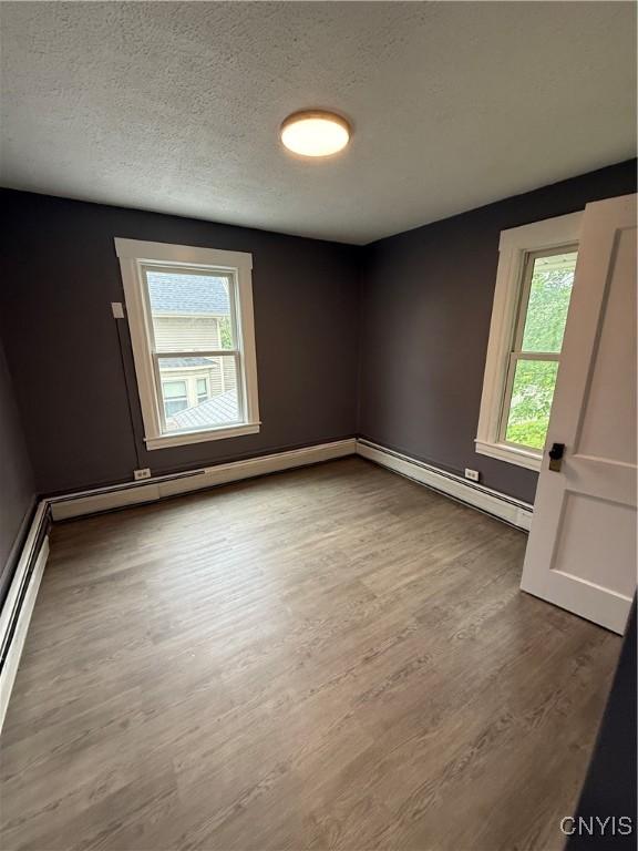 37 Peacock St, Auburn, NY 13021 - spare room featuring a baseboard radiator, wood finished floors, a textured ceiling, and a baseboard heating unit