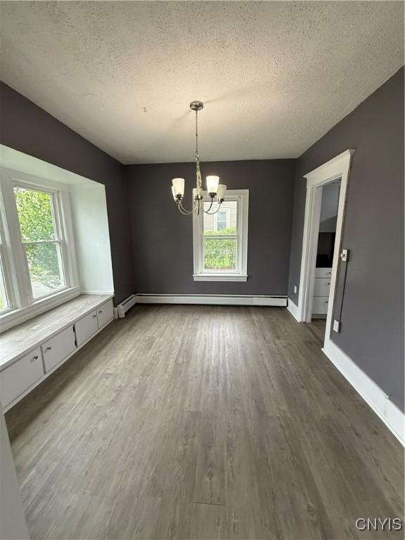 37 Peacock St, Auburn, NY 13021 - unfurnished dining area with healthy amount of natural light, a textured ceiling, a baseboard radiator, a chandelier, and dark wood finished floors