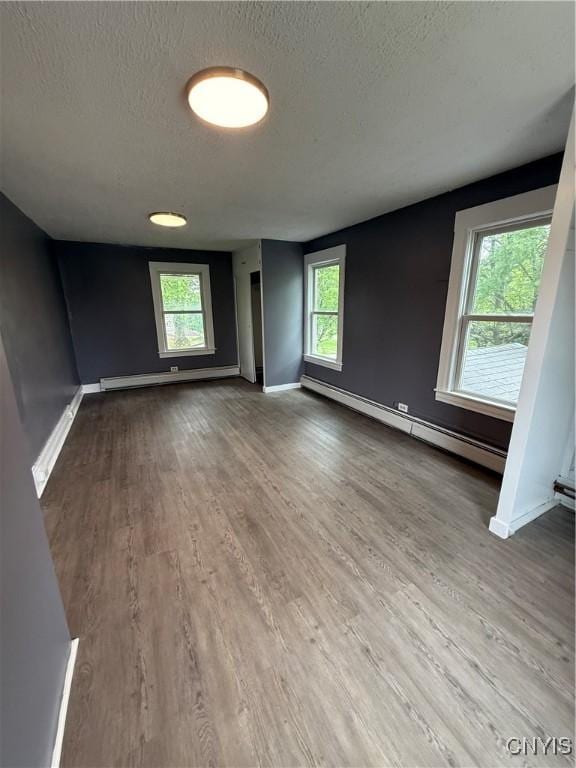 37 Peacock St, Auburn, NY 13021 - unfurnished room featuring a baseboard radiator, a textured ceiling, wood finished floors, and plenty of natural light
