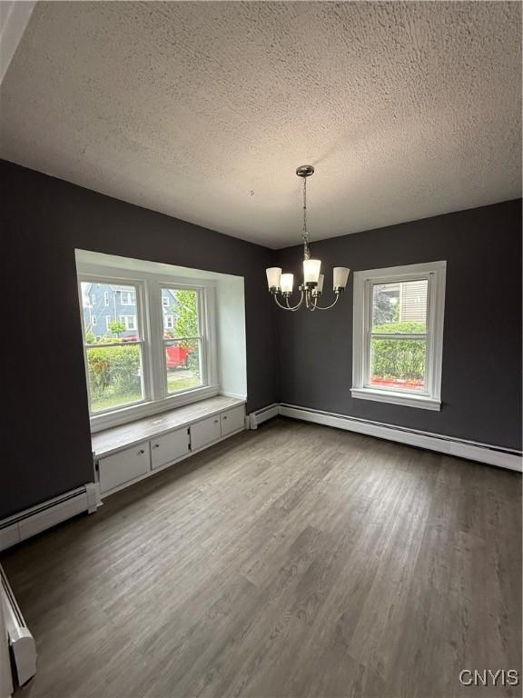 37 Peacock St, Auburn, NY 13021 - unfurnished dining area featuring a chandelier, a textured ceiling, wood finished floors, and a baseboard radiator