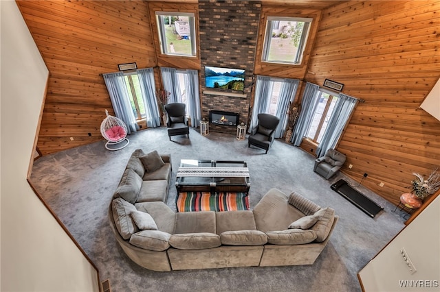 2160 Robert Dr, Niagara, NY 14304 - carpeted living area with plenty of natural light, wooden walls, a brick fireplace, and a towering ceiling