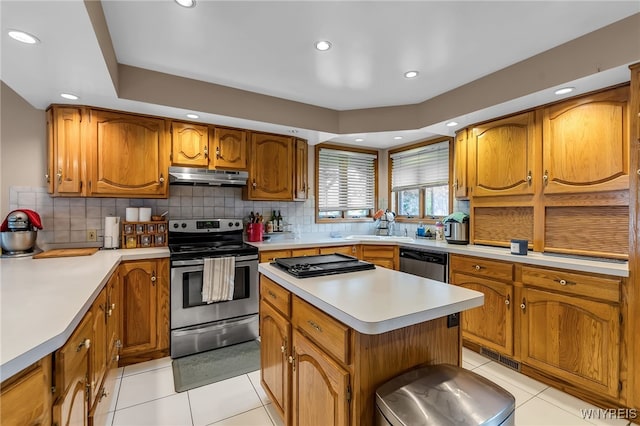 2160 Robert Dr, Niagara, NY 14304 - kitchen with appliances with stainless steel finishes, under cabinet range hood, brown cabinets, light countertops, and light tile patterned floors