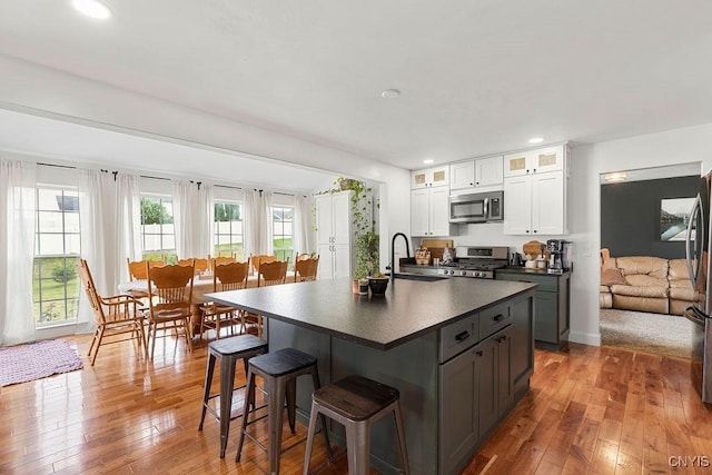 5418 Quamby Rd, Clay, NY 13041 - kitchen with stainless steel appliances, dark countertops, a breakfast bar, light wood-style flooring, and recessed lighting