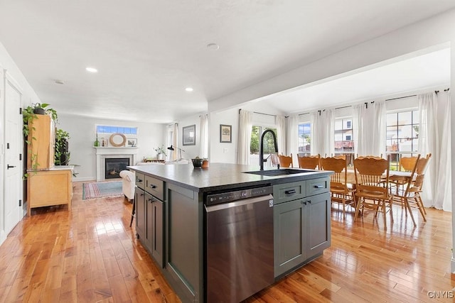 5418 Quamby Rd, Clay, NY 13041 - kitchen with stainless steel dishwasher, light wood-type flooring, a fireplace, gray cabinets, and a center island with sink