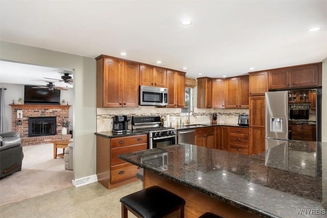 68 Dover Dr, West Seneca, NY 14224 - kitchen featuring stainless steel appliances, ceiling fan, brown cabinetry, open floor plan, and dark stone counters