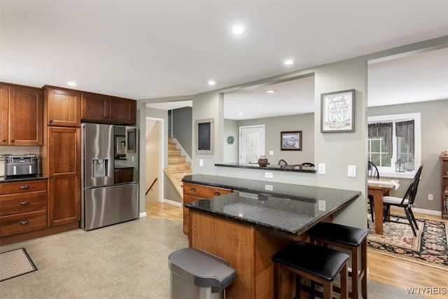 68 Dover Dr, West Seneca, NY 14224 - kitchen with stainless steel refrigerator with ice dispenser, a kitchen bar, recessed lighting, dark stone countertops, and brown cabinetry