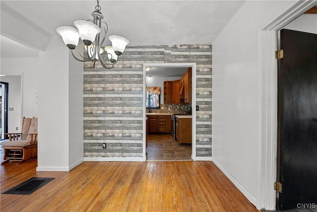 119 Kenneth Ave, Onondaga, NY 13120 - unfurnished dining area featuring a chandelier, hardwood / wood-style floors, and wooden walls