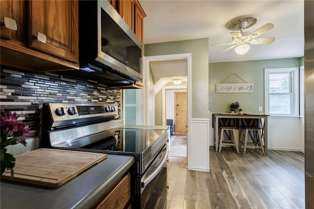 387 Brandon Rd, Irondequoit, NY 14622 - kitchen with appliances with stainless steel finishes, light wood-style floors, decorative backsplash, wainscoting, and ceiling fan