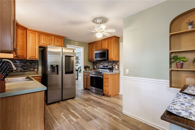 387 Brandon Rd, Irondequoit, NY 14622 - kitchen featuring appliances with stainless steel finishes, ceiling fan, wainscoting, light wood-style flooring, and backsplash