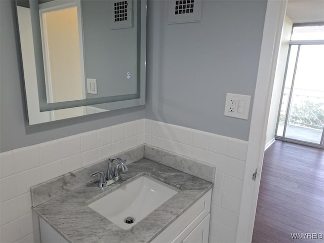 1088 Delaware Ave Unit 6C, Buffalo, NY 14209 - bathroom featuring tile walls, plenty of natural light, vanity, a wainscoted wall, and wood finished floors